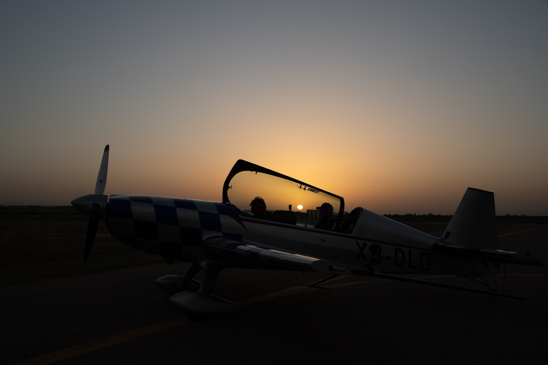 Extra 330 XB-DLG with sunset reflected in the canopy, two pilots inside